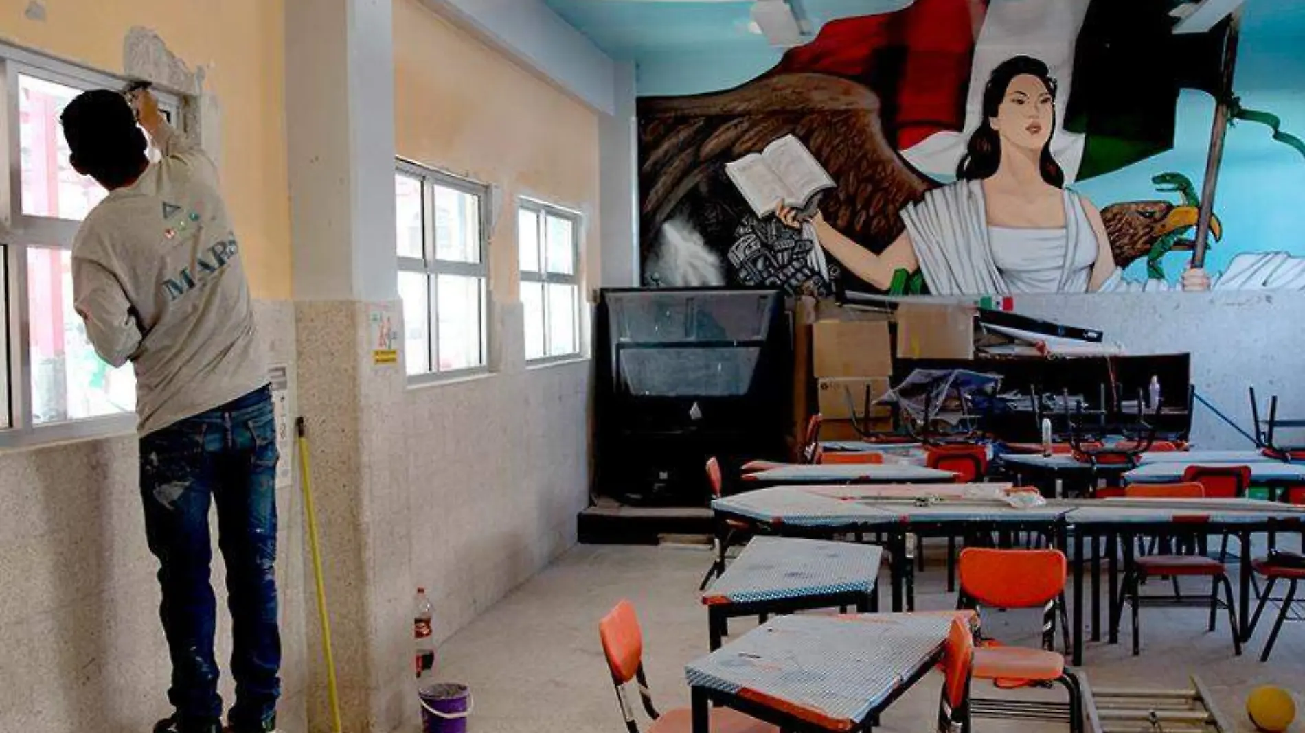 Personal de apoyo realiza labor de limpieza en un salón de clases ante el panorama de un posible regreso a clases